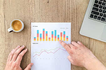 Businessman analyzing financial charts on wooden desk with coffee