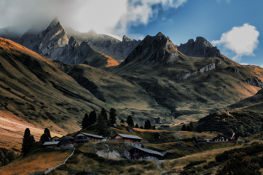 Alpine Mountain Village with Wooden Cabins and Clouds