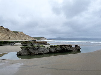 Serene coastal landscape with mossy rocks and sandy beach