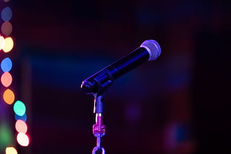 Black microphone on stand with colorful bokeh lights in dark background