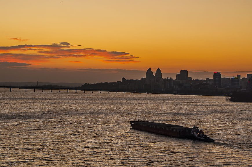 Cargo barge on river at sunset with city skyline
