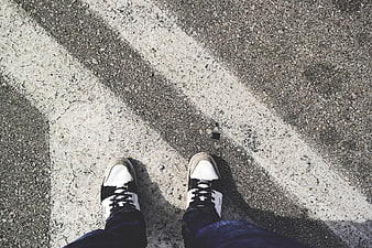 First-person view of sneakers on asphalt road with white lines
