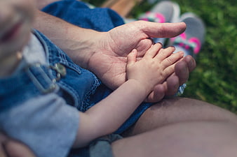 Close-up of father holding baby's hand outdoors