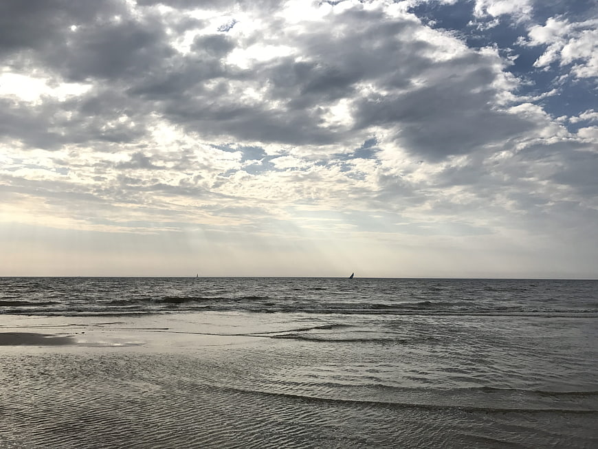 Dramatic cloudy sky over calm sea with distant sailboats