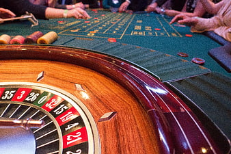 Close-up of wooden roulette wheel and green casino table