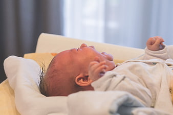 Close-up of newborn baby crying while lying on bed