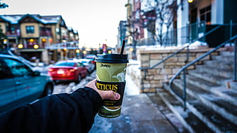 Hand holding coffee cup on snowy city street