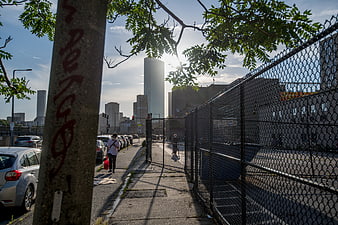 Urban Sidewalk with Chain Link Fence and City Skyline