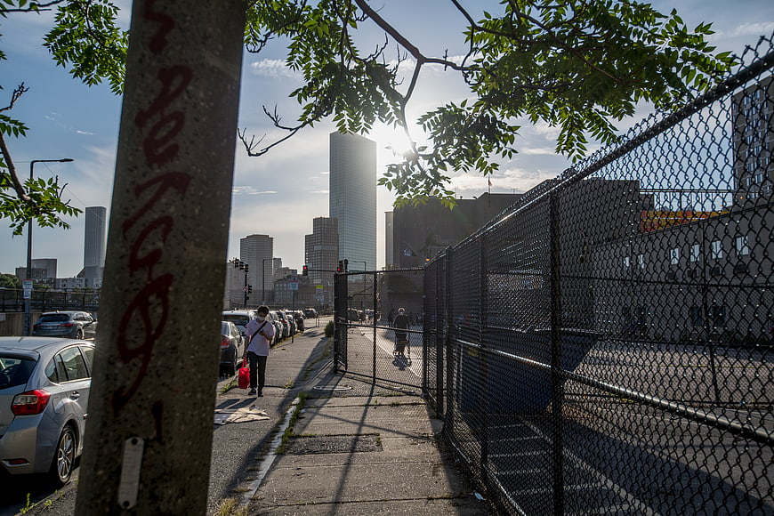 Urban Sidewalk with Chain Link Fence and City Skyline