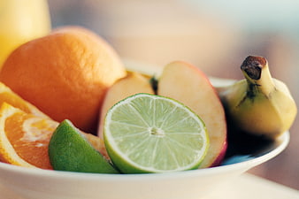 Fresh fruit bowl with lime, orange, apple, and banana
