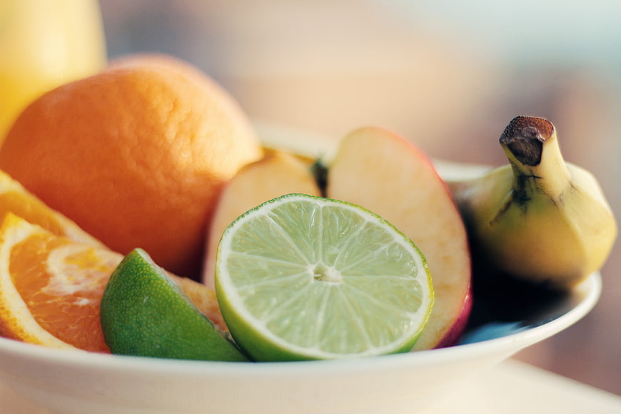 Fresh fruit bowl with lime, orange, apple, and banana