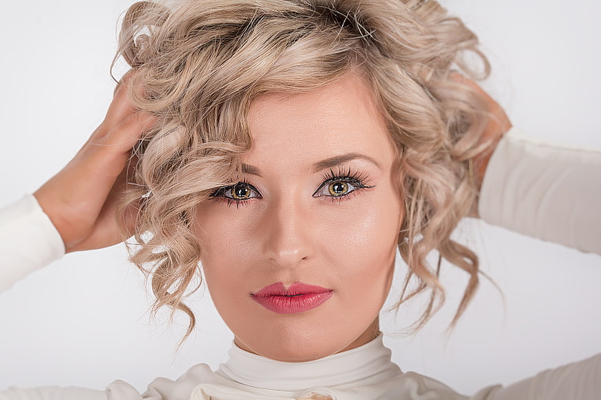 Beautiful blonde woman with curly hair and pink lipstick