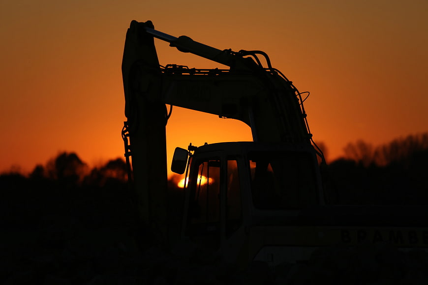 Excavator Silhouette Against Vibrant Orange Sunset Sky