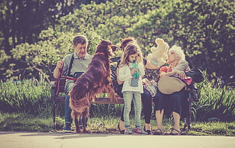 Multi-generational family with dog relaxing on park bench