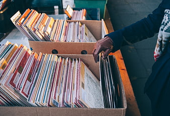 Person browsing vintage vinyl records in cardboard boxes