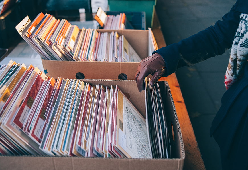 Person browsing vintage vinyl records in cardboard boxes