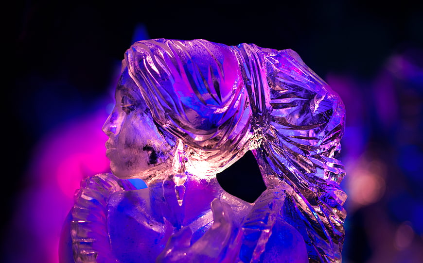 Purple and blue lit ice sculpture of a woman's profile