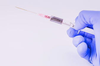 Gloved Hand Holding Medical Syringe with Liquid