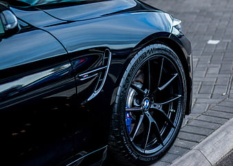 Close-up of black BMW M4 wheel and side vent
