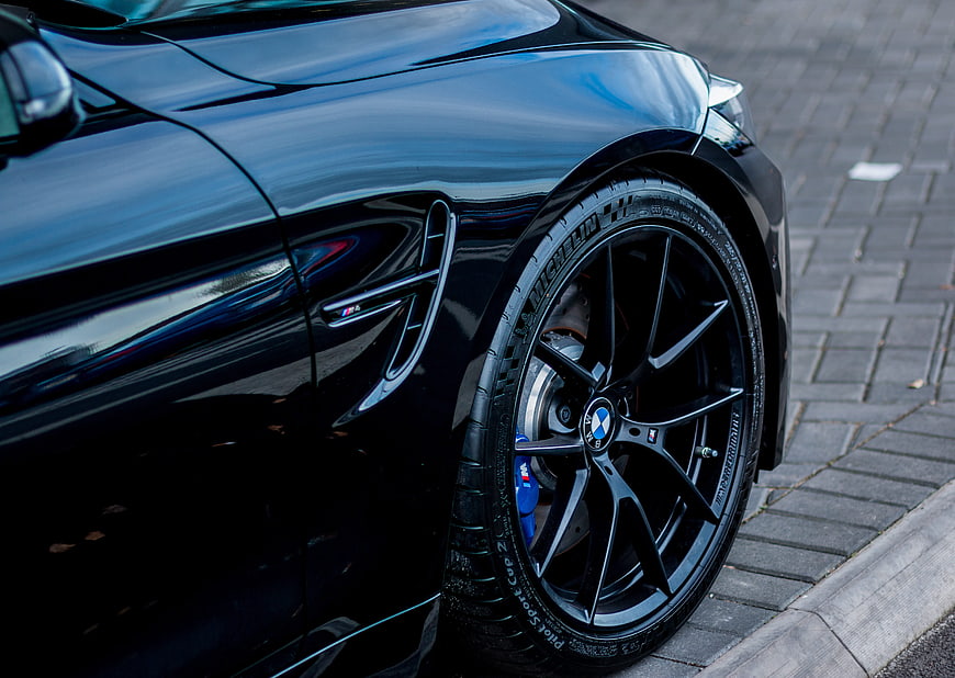 Close-up of black BMW M4 wheel and side vent