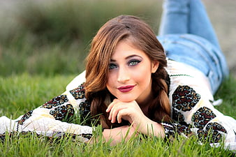 Young woman in traditional embroidered blouse lying on grass