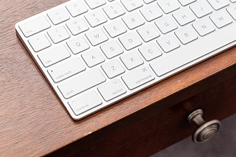 White Wireless Keyboard on Wooden Desk Surface