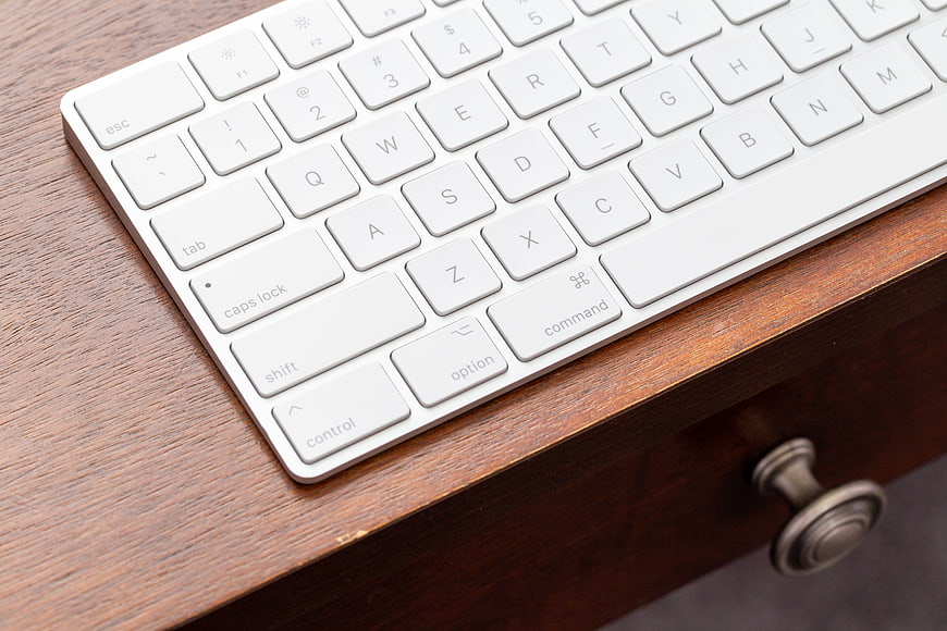 White Wireless Keyboard on Wooden Desk Surface