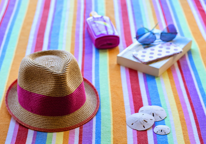 Summer beach accessories on colorful striped towel