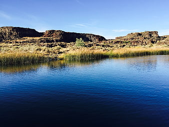 Serene Blue Lake with Rocky Cliffs and Reeds