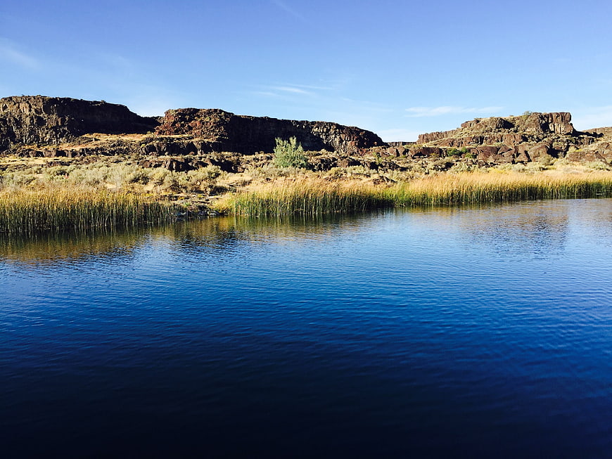 Serene Blue Lake with Rocky Cliffs and Reeds