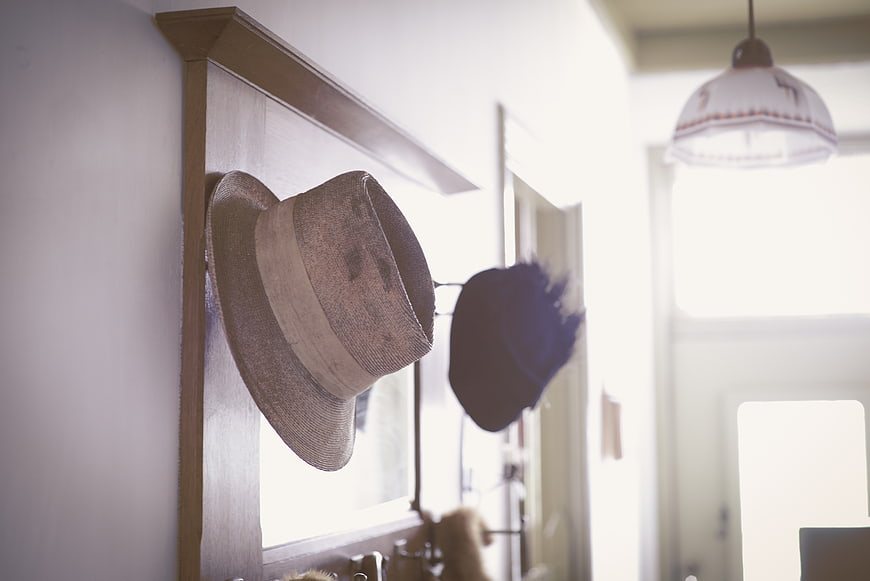 Vintage straw hat hanging on wooden coat rack in hallway