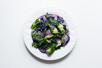 Top view of sauteed kale, broccoli, and red cabbage on white plate