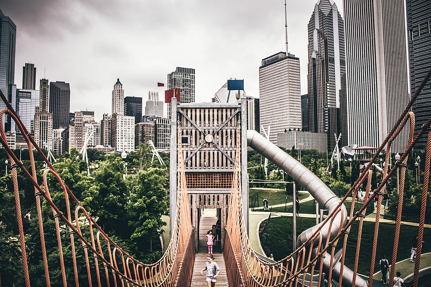 Children playing on suspension bridge in Chicago park with skyline