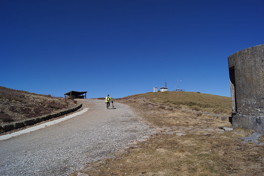 Hiker with bicycle on mountain road under blue sky