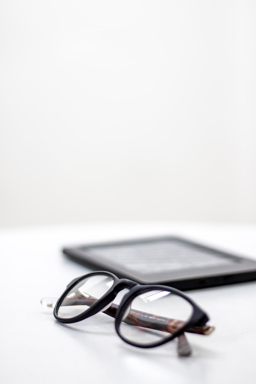 Black Eyeglasses and E-reader on White Surface