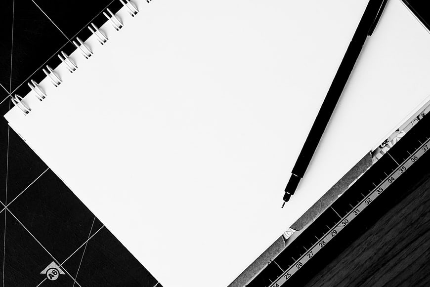 Black and white notebook with pen and ruler on desk