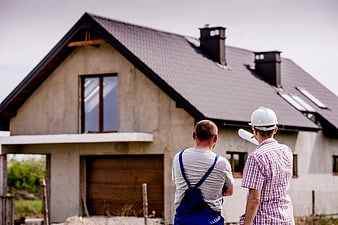Two construction workers inspecting a modern house under construction