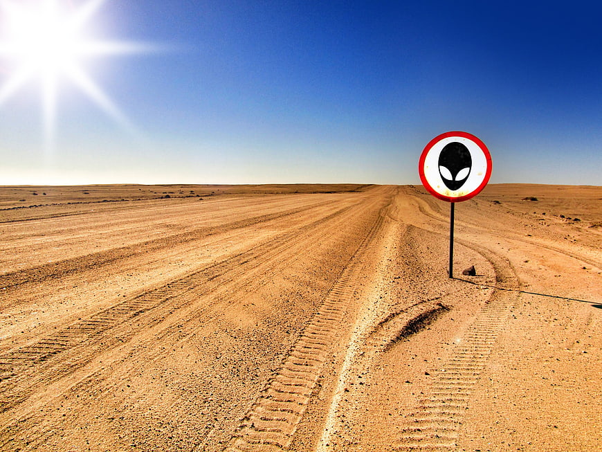 Alien Warning Sign on Desert Road Under Bright Sun