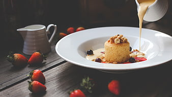 Pouring caramel sauce on a mini sponge cake with strawberries