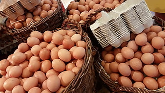 Fresh brown eggs in woven baskets at a market stall