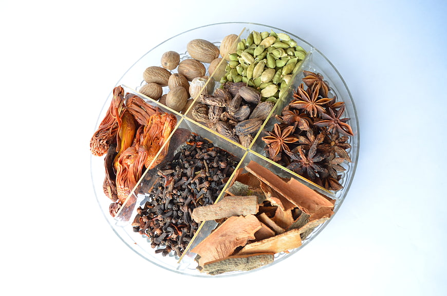 Assorted Whole Spices In Divided Glass Plate On White Background