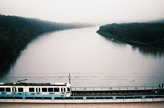 Train crossing bridge over misty river landscape