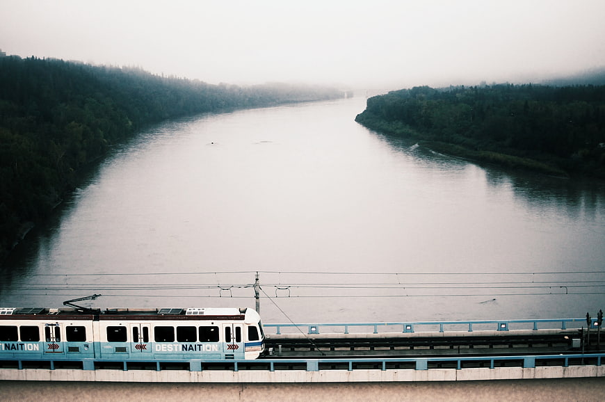 Train crossing bridge over misty river landscape