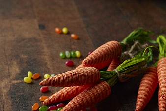 Handmade yarn carrots with jelly beans on rustic wood
