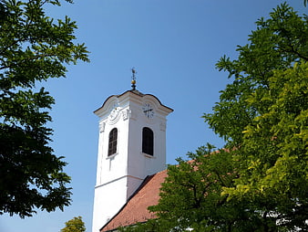White church tower with clock against blue sky