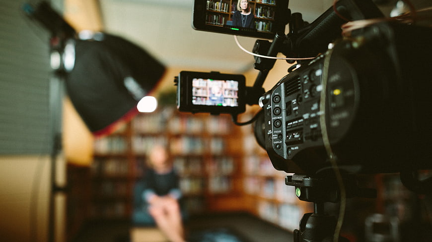 Professional video camera filming interview in library setting