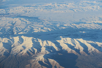 Aerial view of snow-covered mountain ranges with deep shadows