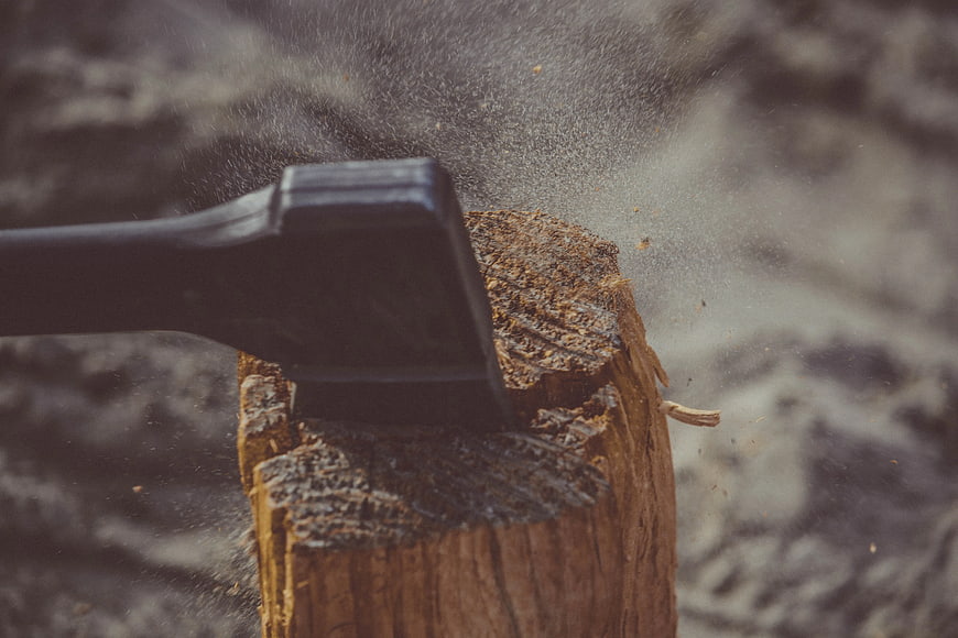 Black Axe Splitting Wood with Flying Sawdust