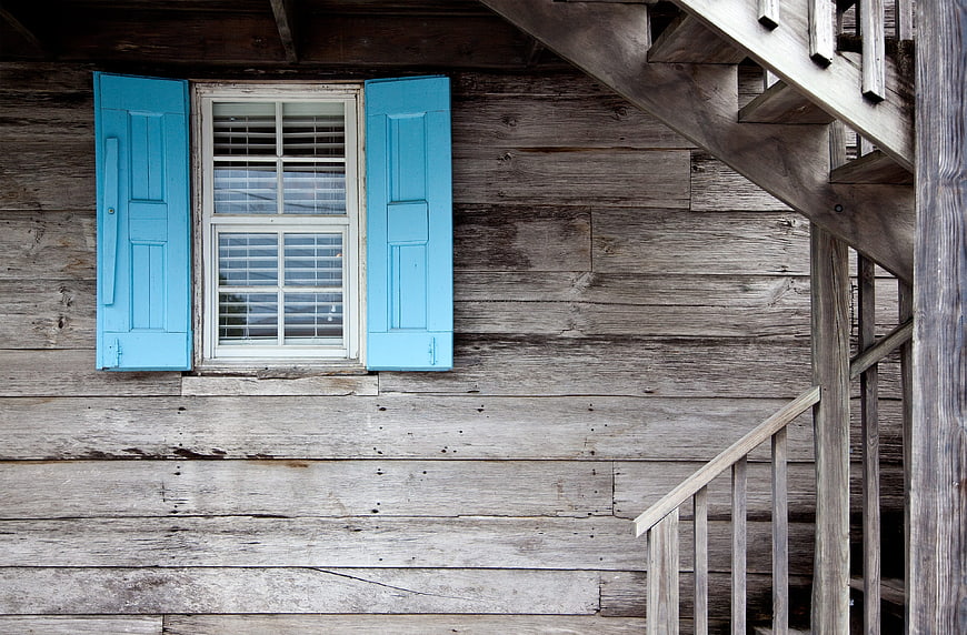 Rustic wooden house facade with blue shutters and stairs