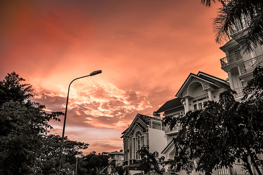 Dramatic orange sunset sky over suburban houses and street lamp